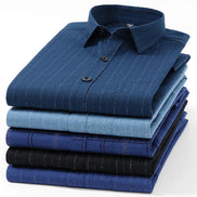 A stack of folded long-sleeve dress shirts in various shades of blue, including navy, light blue, and black, with some shirts featuring subtle vertical pinstripes.