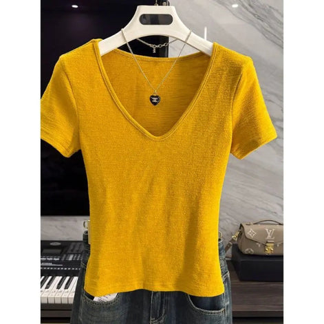 A bright yellow short-sleeve V-neck knit top displayed on a white hanger, styled with a silver necklace and paired with blue jeans in an indoor boutique setting.