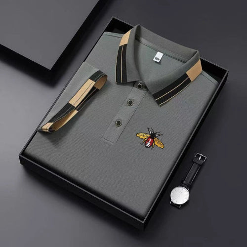 Gray polo shirt with bee emblem and watch on a dark background