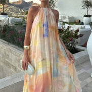 Woman in a colorful dress standing on a rooftop with a scenic view and outdoor furniture.