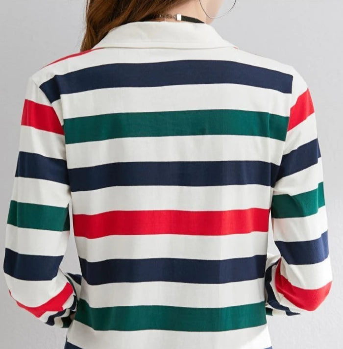 A woman shown from the back wearing a long-sleeve collared shirt with horizontal stripes in white, navy blue, green, and red.
