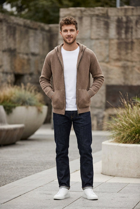 A brown ribbed knit zip-up hoodie jacket with a hood and front pockets, displayed on a wooden hanger over a white t-shirt 