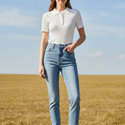 A white short-sleeve ribbed knit polo shirt with a collar and decorative button placket, hanging on a wooden hanger against a split gray and marble background.