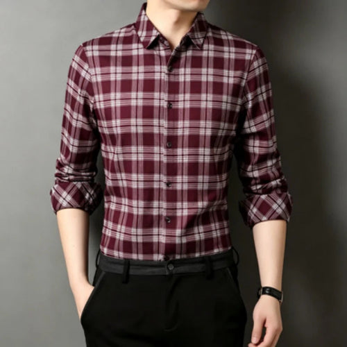 A man wearing a long-sleeve button-up plaid shirt in burgundy and white, paired with black trousers, shown against a dark gray background.
