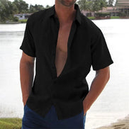 Man wearing a black open-neck shirt with a blurred background