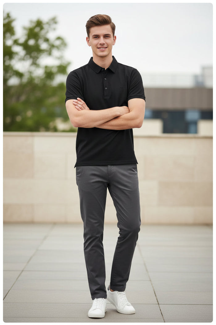 A black short-sleeve polo shirt hanging on a black hanger in a retail clothing display, with other garments visible in the background.