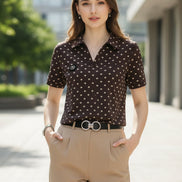 A woman wearing a brown short-sleeve polo shirt with a white polka dot pattern, paired with beige trousers and a black belt with a silver buckle.