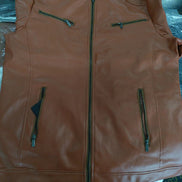 Brown leather vest with multiple zippers on a reflective surface