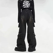 Back view of a model wearing washed black baggy cargo jeans with back patch pockets, side flap pockets, and hanging straps against a white background.⠋