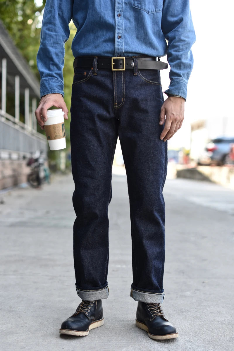 Person wearing blue denim shirt and jeans standing on a street.