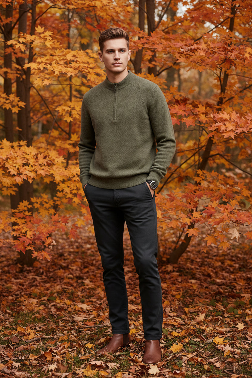 Green half-zip sweater on a gray surface with a watch beside it