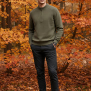 Green half-zip sweater on a gray surface with a watch beside it