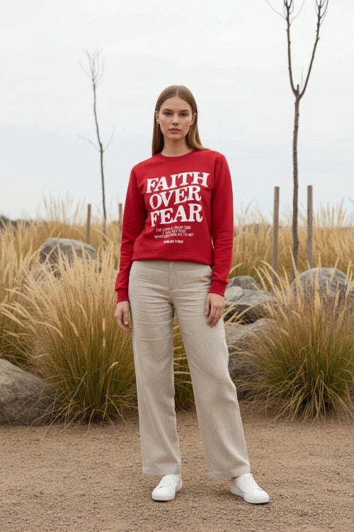 Red sweatshirt with 'Faith Over Fear' text on a wooden background