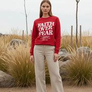 Red sweatshirt with 'Faith Over Fear' text on a wooden background