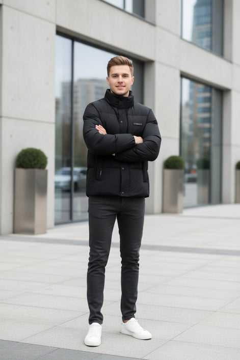 A black puffer jacket hanging on a clothing rack in a retail store setting, with promotional graphic overlays on the left highlighting warmth, softness, and down content. The jacket has a high collar, front zipper and snap closure, and a small chest label.