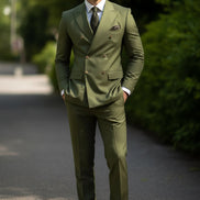Green suit with a patterned tie and pocket square against a blurred outdoor background