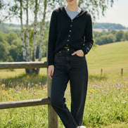 Person wearing a black cardigan with buttons in a blurred indoor setting