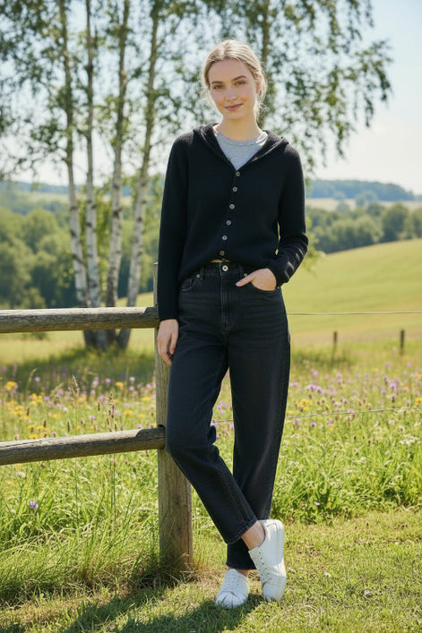 Person wearing a black cardigan with buttons in a blurred indoor setting