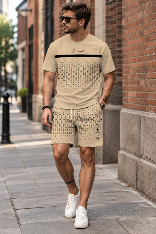 A man wearing a beige short-sleeve t-shirt and matching patterned shorts, leaning against a stone