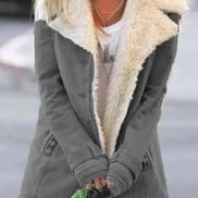 Woman outdoors wearing a gray coat with wide cream fleece-look lapels, front pockets and cuff tabs over a white top