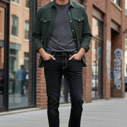 Person wearing black jeans and brown boots against a gray background