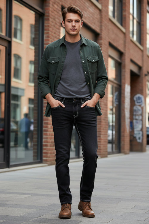 Person wearing black jeans and brown boots against a gray background