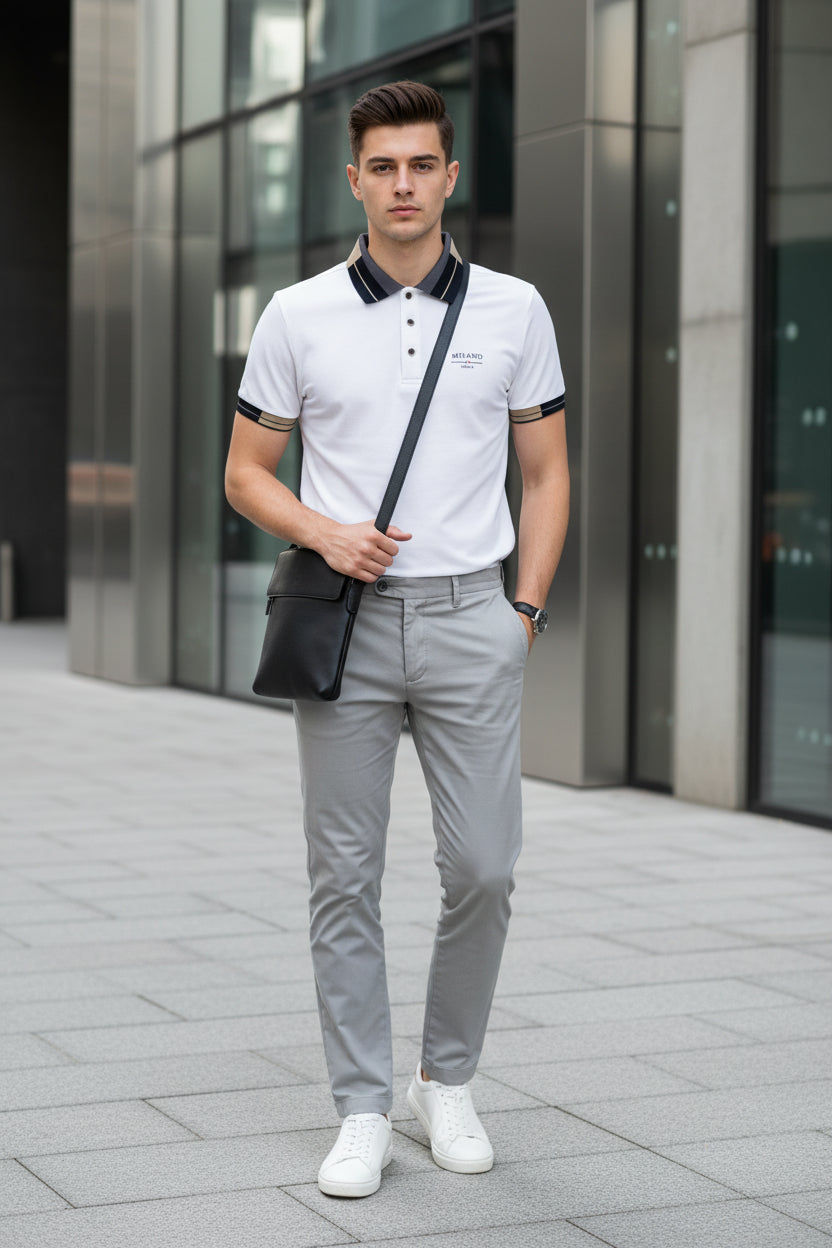 White polo shirt with black collar and buttons, accompanied by a gold watch, on a dark background.