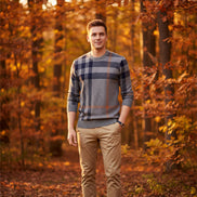 Person wearing a gray and blue plaid sweater on a dark background