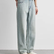 Person wearing light blue jeans and a white shirt on a plain background