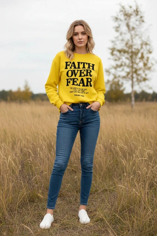 Yellow sweatshirt with 'Faith Over Fear' text on a wooden background