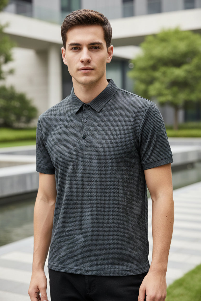 Gray textured polo shirt on a hanger with a hand touching the fabric.