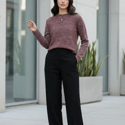 A woman wearing a marled burgundy knit sweater with a crew neck, styled with gold earrings 