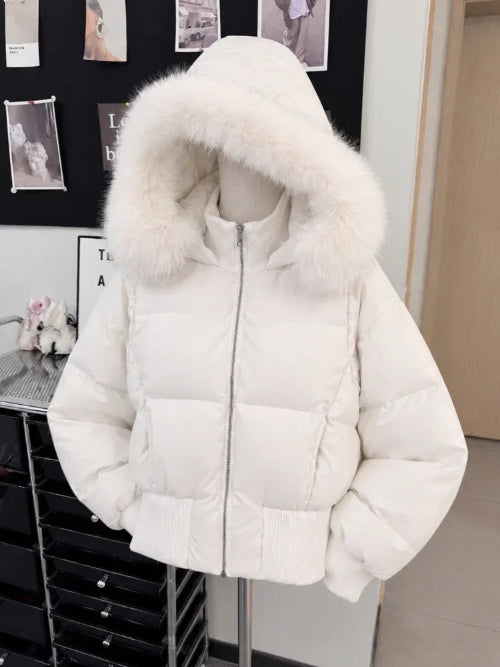 A white puffer jacket with a large fluffy faux-fur trimmed hood, displayed on a mannequin torso in an indoor room setting.
