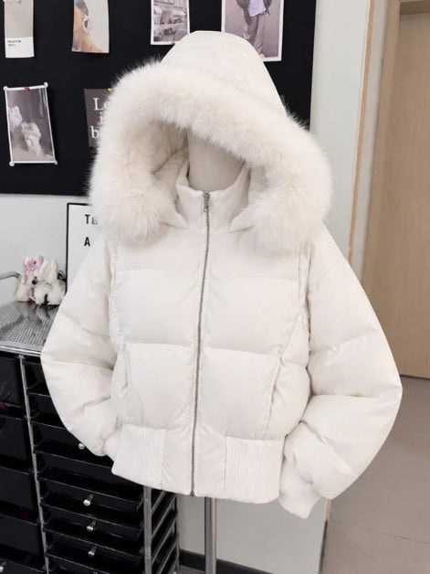 A white puffer jacket with a large fluffy faux-fur trimmed hood, displayed on a mannequin torso in an indoor room setting.