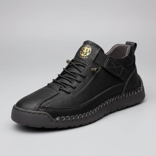Black leather sneaker with a brand logo on a wooden surface