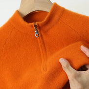 Orange fleece pullover with a zipper on a hanger, held by a hand.