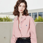Woman wearing a pink shirt with colorful buttons against a plain background