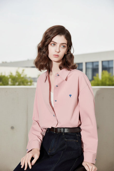 Woman wearing a pink shirt with colorful buttons against a plain background