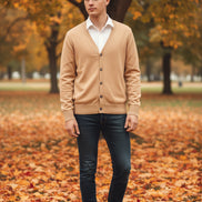 Beige cardigan over a white shirt on a wooden hanger against a wooden cabinet background.