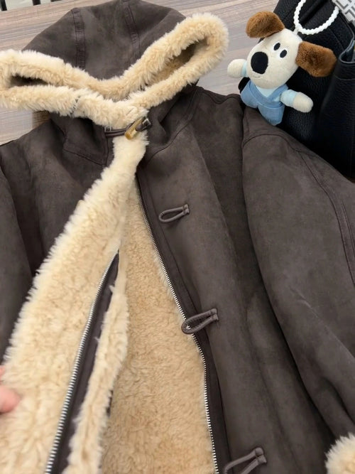 Close-up of a brown hooded jacket held open to show cream fleece-look lining, an inner zipper and outer toggle fastenings