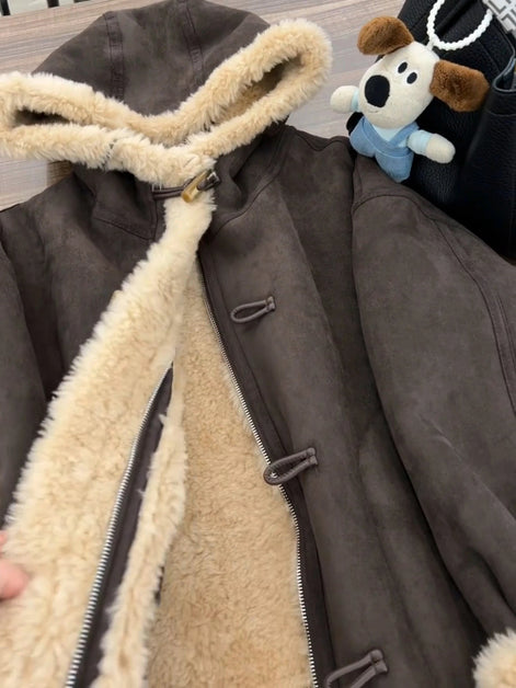 Close-up of a brown hooded jacket held open to show cream fleece-look lining, an inner zipper and outer toggle fastenings