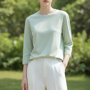 Person wearing a light green long-sleeve shirt against a neutral background