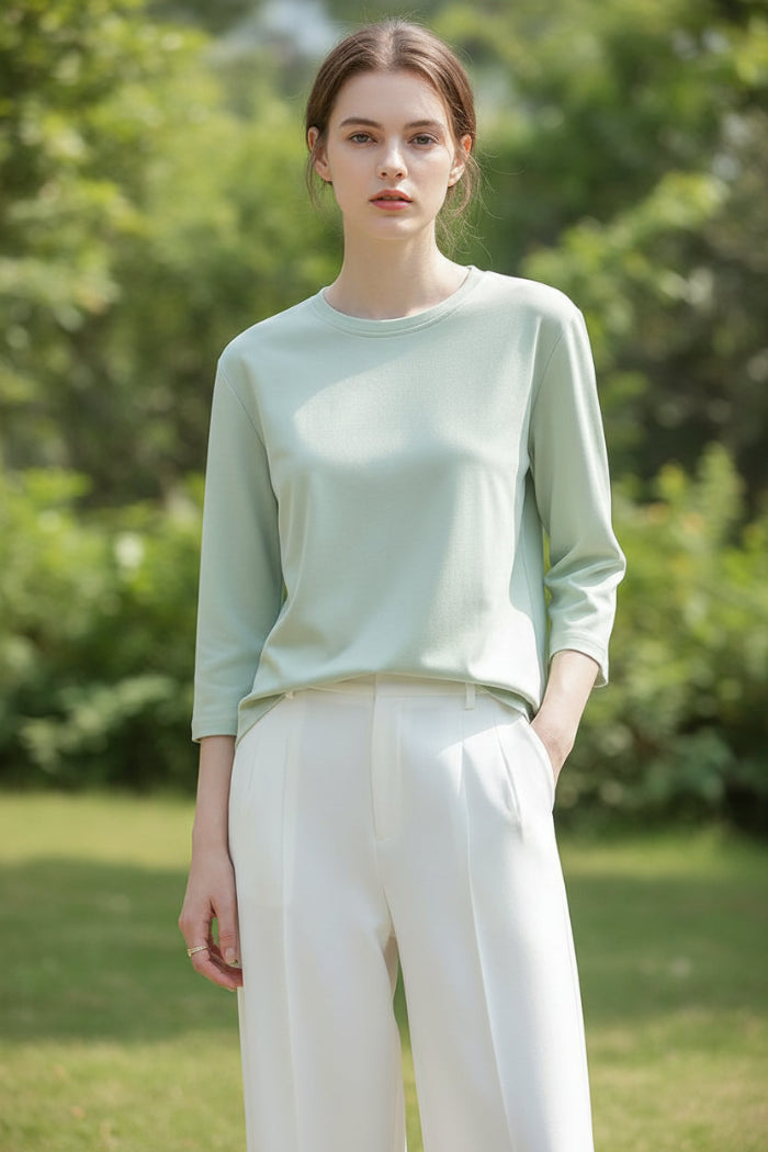 Person wearing a light green long-sleeve shirt against a neutral background