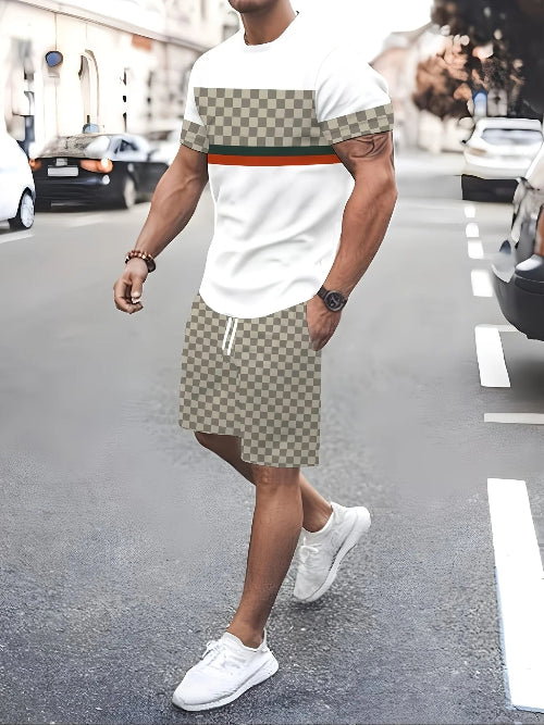 A man walking on a city street wearing a white t-shirt with a beige and brown checkerboard pattern 