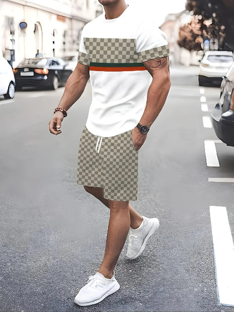 A man walking on a city street wearing a white t-shirt with a beige and brown checkerboard pattern 