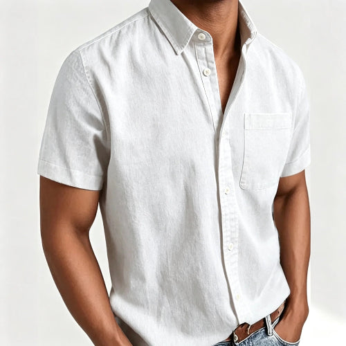 A man wearing a white short-sleeve button-up shirt with a chest pocket, paired with blue jeans and a brown belt, shown 