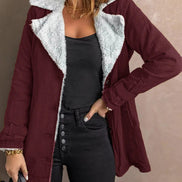 Woman wearing a dark red jacket with white fleece-look lining, wide lapels and buckled cuffs over a black top and jeans