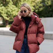 Person wearing a red puffer jacket against a beige wall