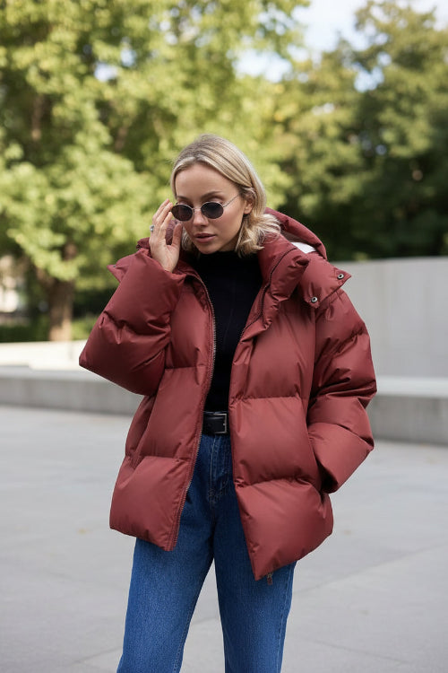 Person wearing a red puffer jacket against a beige wall