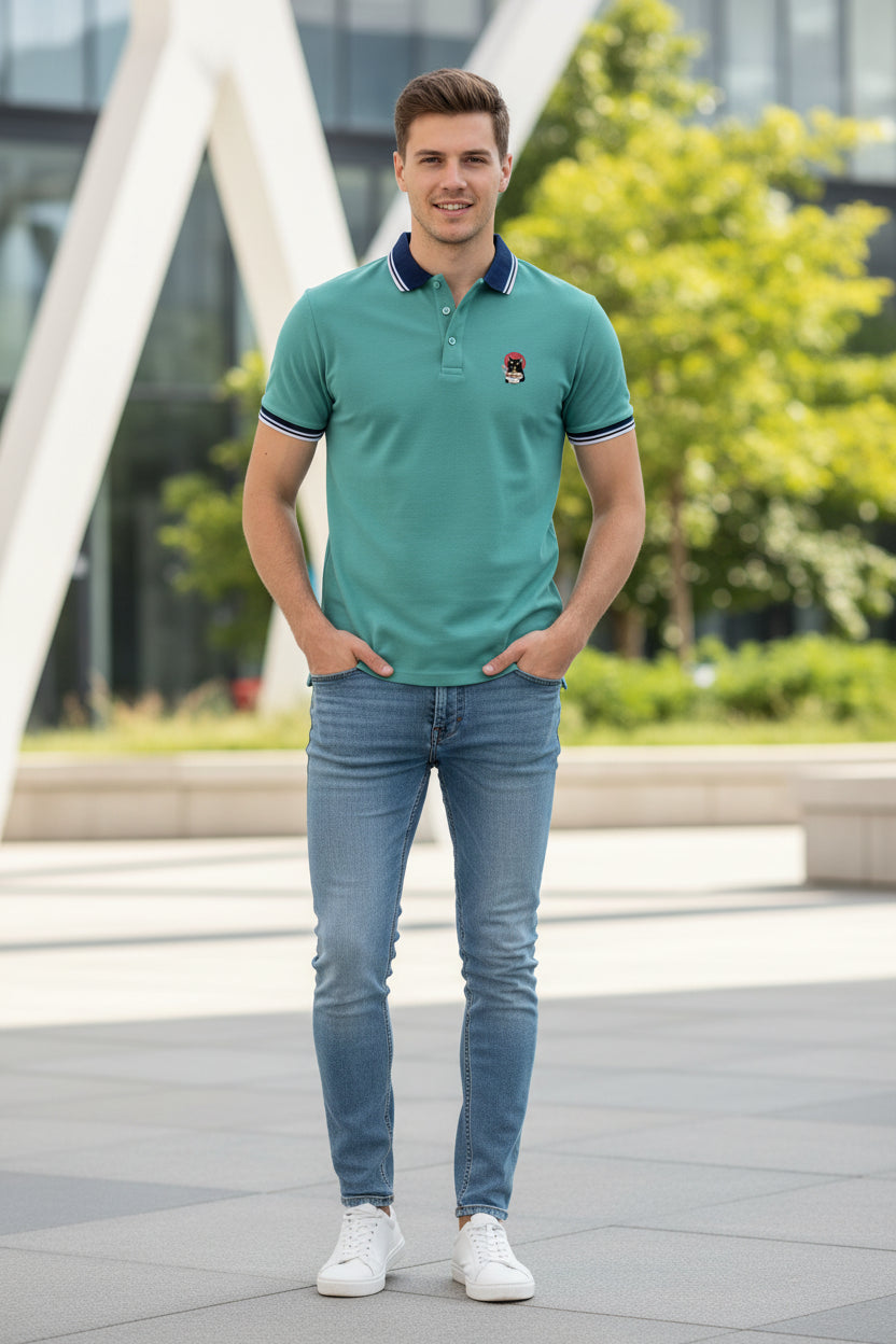 A men's short-sleeve polo shirt in a light teal color, featuring a navy blue and white striped collar, matching striped sleeve cuffs, a partial button placket, and a small cartoon dog graphic on the left chest.